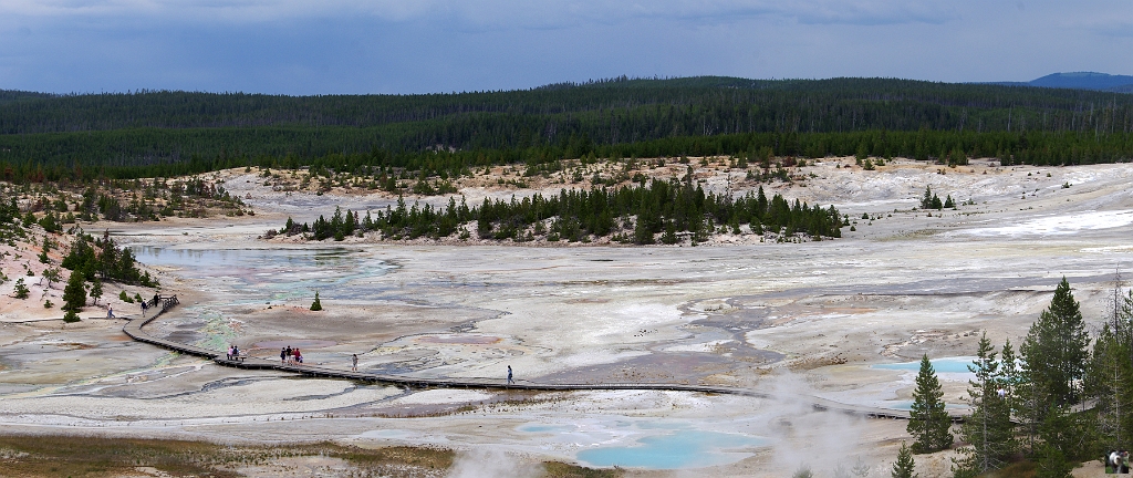 0940_0941_M.JPG - De grandes zones occupées par des geysers et solfatares.Yellowstone se trouve probablement à la verticale d'un point chaud qui, il y a 600 000 ans, entraîna la formation d'une chambre magmatique peu profonde. En grossissant, cette chambre magmatique poussa la croûte terrestre, formant un dôme volumineux. Des fractures apparurent en bordure du dôme, provoquant une éruption d'une extrême violence. Après l'évacuation de ce magma, la voûte du dôme s'effondra, formant une caldeira de 3 000 km². La lave commença à emplir cette caldeira pendant les 500 000 ans qui suivirent et c'est cette zone volcanique encore active qui sert de source de chaleur aux geysers et bassins de Yellowstone.